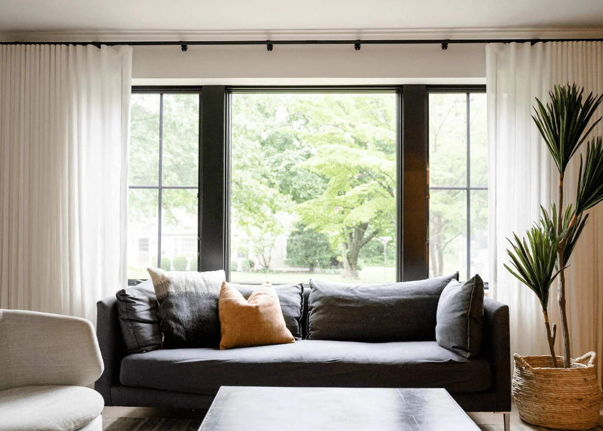 Modern living room with large window and green view.