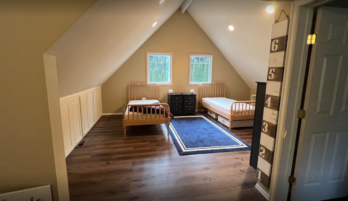 Cozy attic bedroom with twin beds and wooden floor.