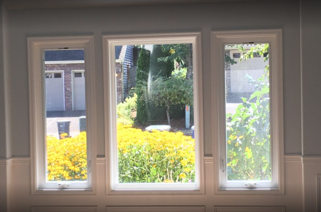 Three-pane window overlooking blooming yellow flowers.