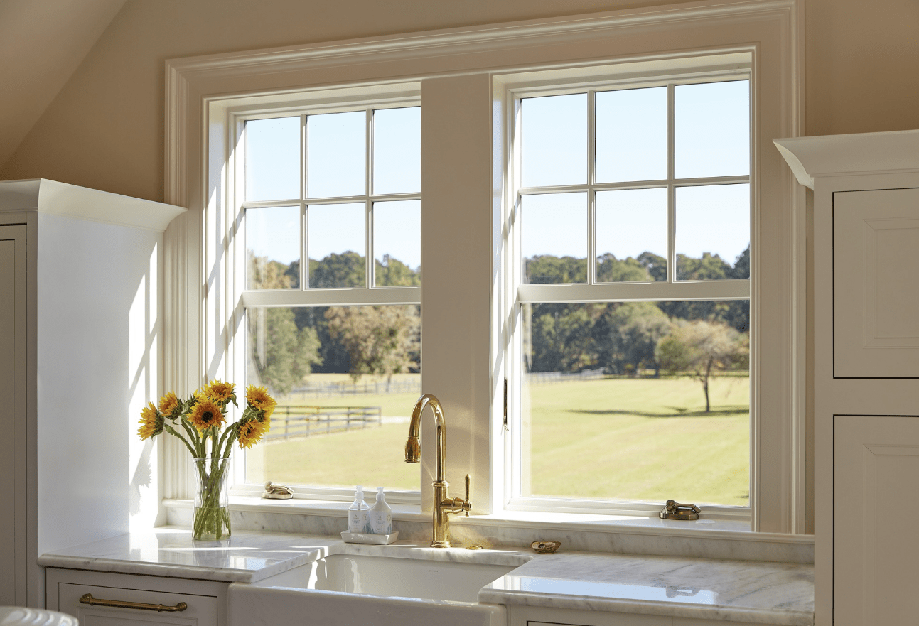 Bright kitchen with large windows and sunflowers on countertop.