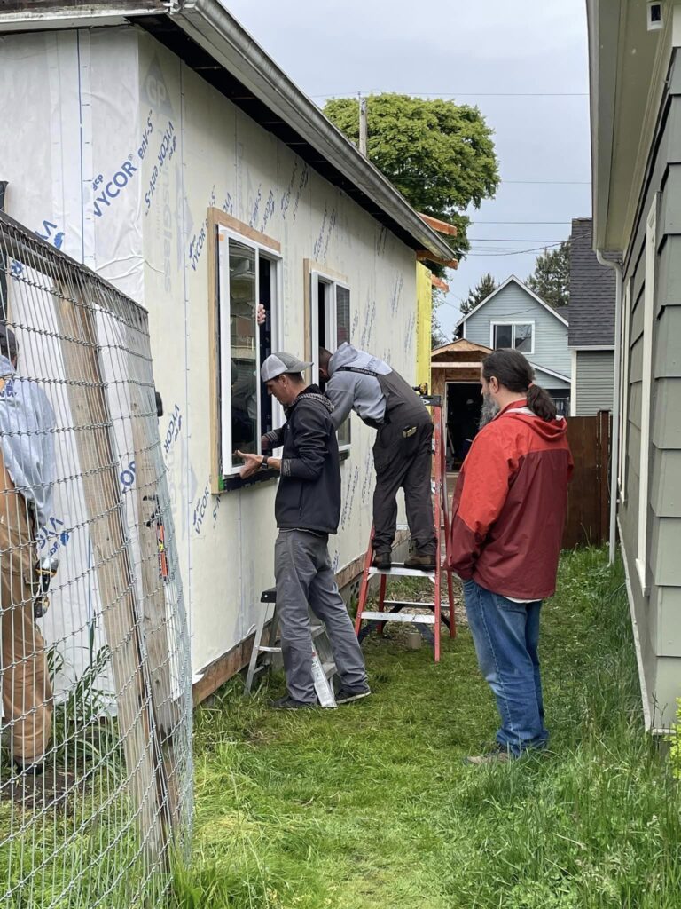 Workers installing windows on house exterior.