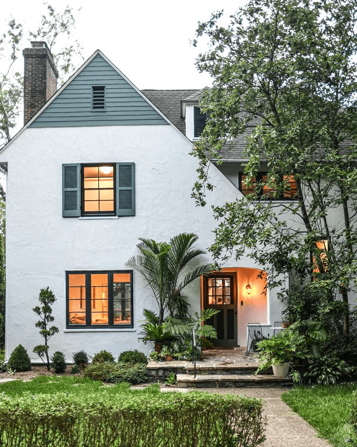 Cozy white house with green shutters and illuminated windows