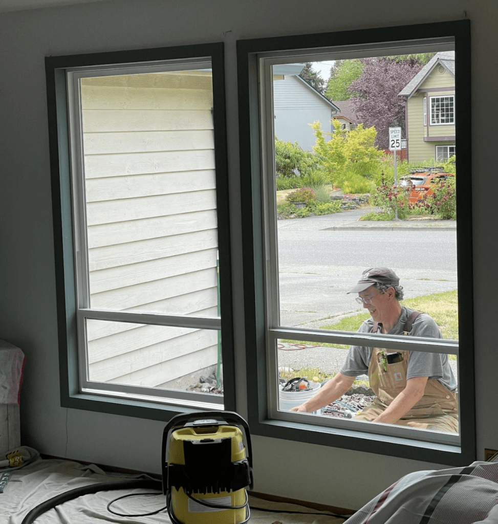 Man working on garden seen through open house windows